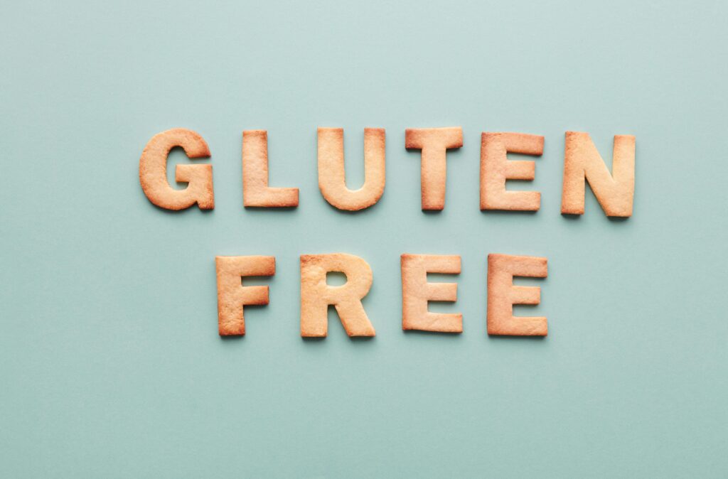 Gluten-free cookie letters form a phrase on a turquoise background, ideal for allergy awareness.
